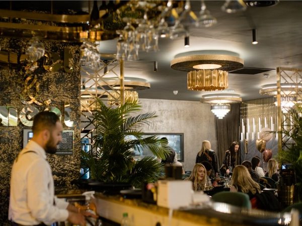 restaurant interior with large ferns and gold lighting