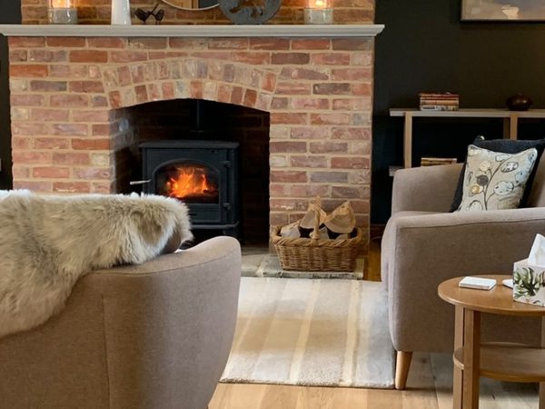 Log burning fire with sheepskin rugs in cosy living room of Taumberland Barns
