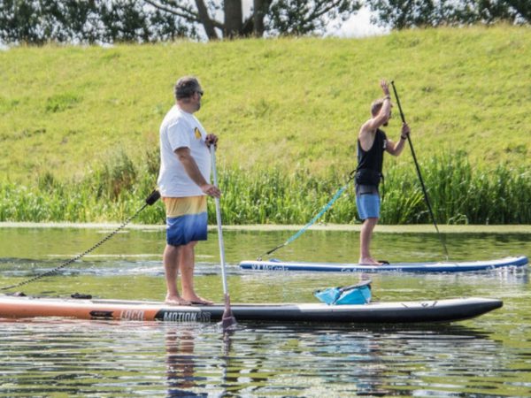 2 men Stand Up Paddleboarding on a river