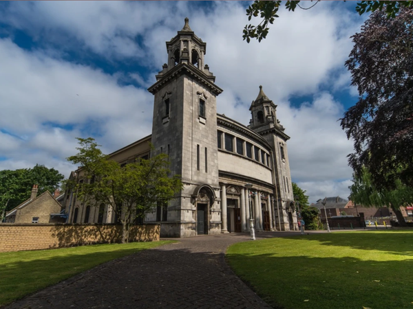 wide angle image of centenary Methodist church with green grass and blue skies